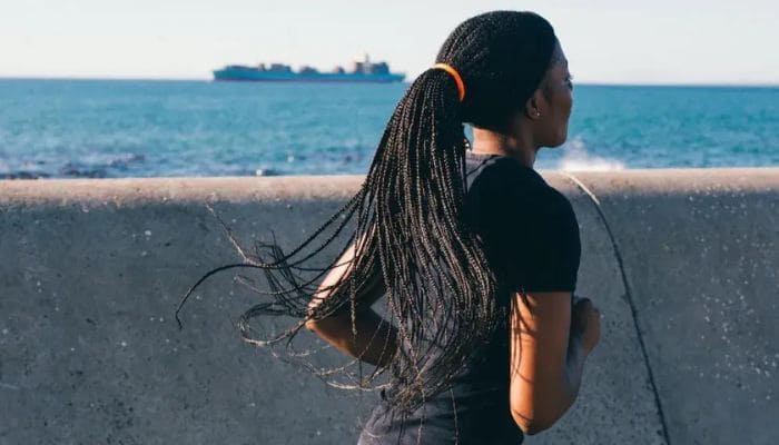 Mulher de cabelo dread look correndo perto do mar