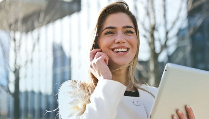 Bela garota sorrindo enquanto segura um tablete