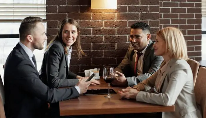 Dois casais bem vestidos fazem reunião em uma mesa de restaurante