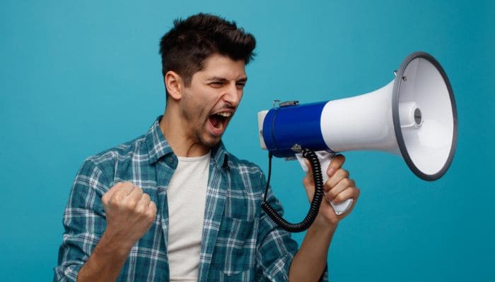 Homem de camisa xadrez gritando em um megafone