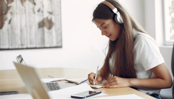 Jovem garota estudando usando notebook e fones de ouvido