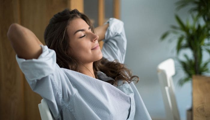 Jovem mulher de cabelos longos com semblante feliz de olhos fechados