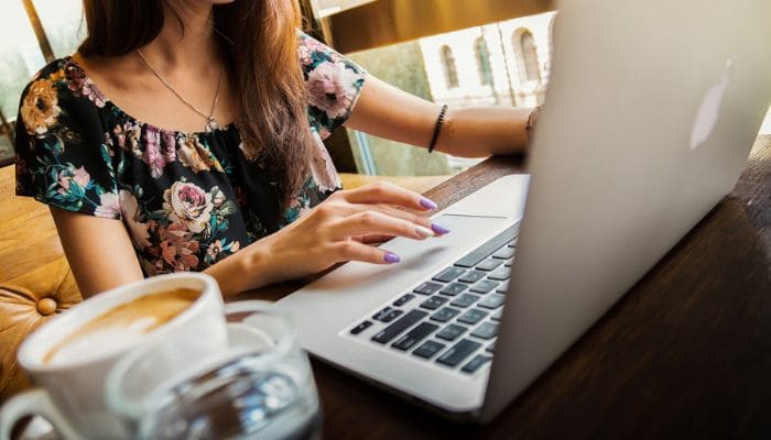 Mulher com sua caneca de café usando um notebook