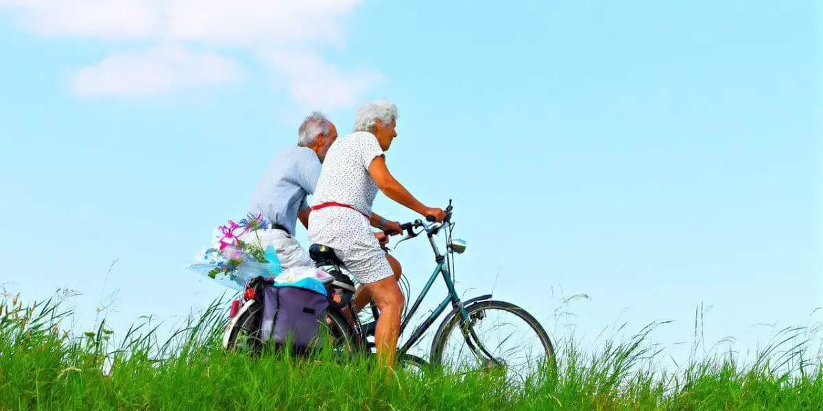 Ciclismo: Casal de idosos andando de bicicleta sob um céu azul.