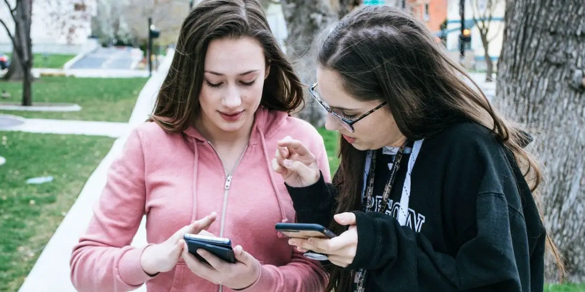 Redes sociais: Duas garotas comparando os conteúdos de seus smartphones.