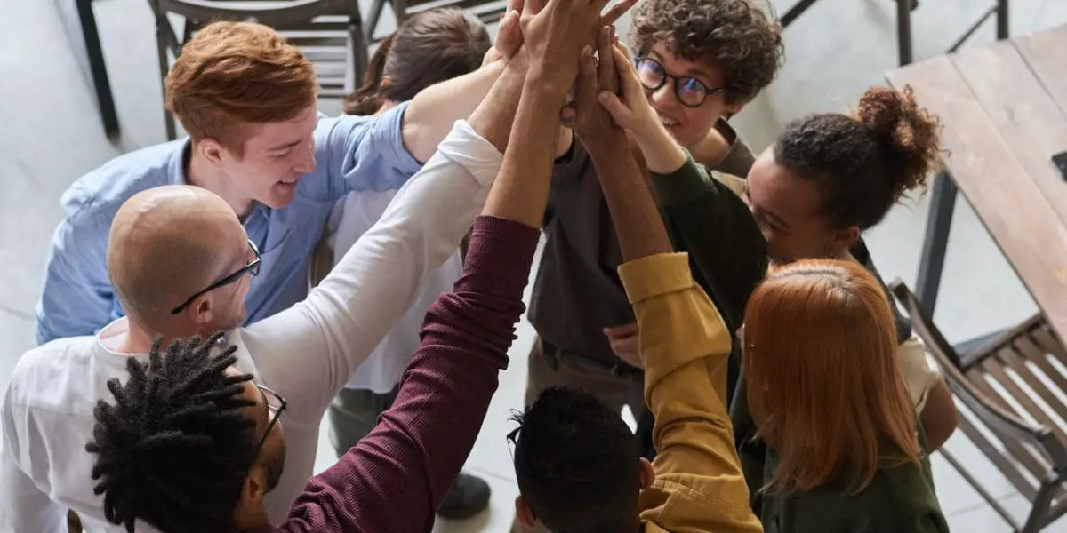 Comunicação assertiva: grupo de amigos fazendo um high five.