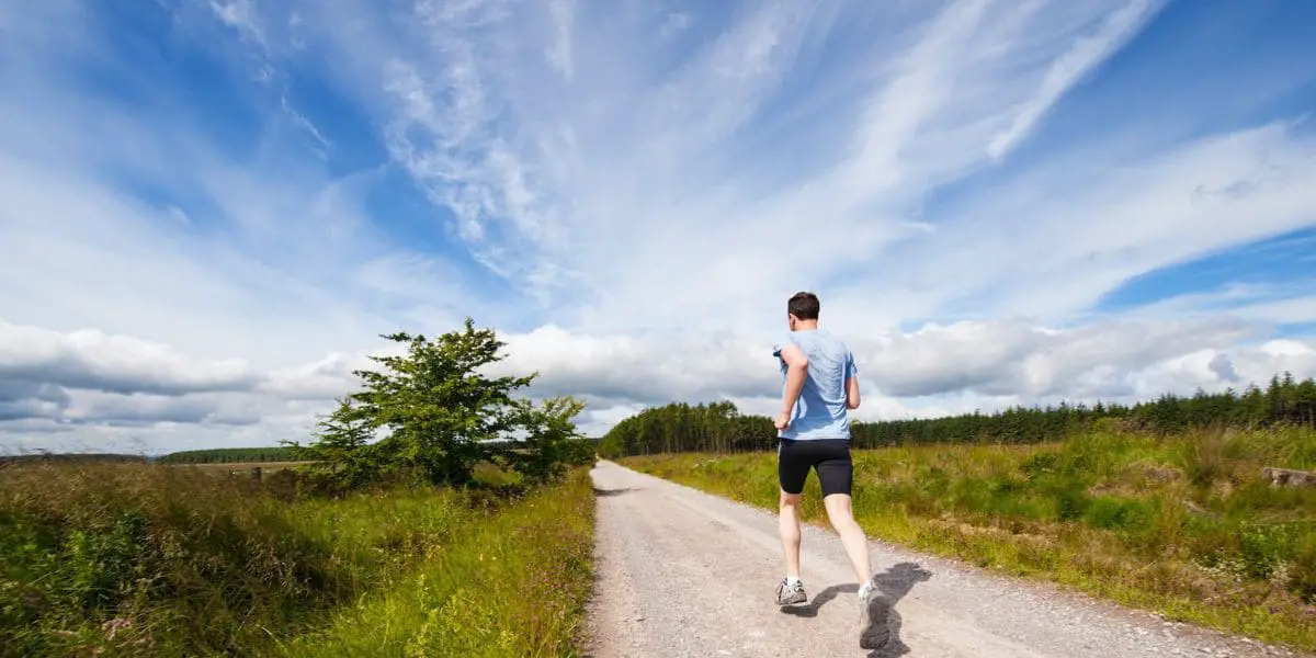 Homem praticando corrida em estrada de terra.