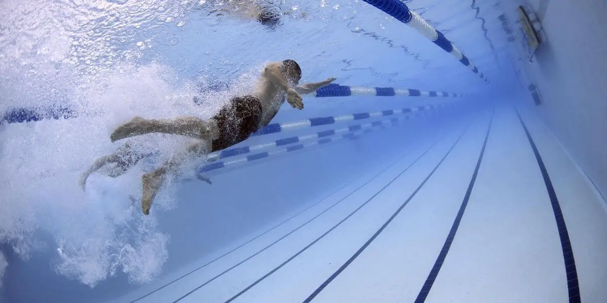 Exercícios aeróbicos: Homem nadando em piscina olímpica.