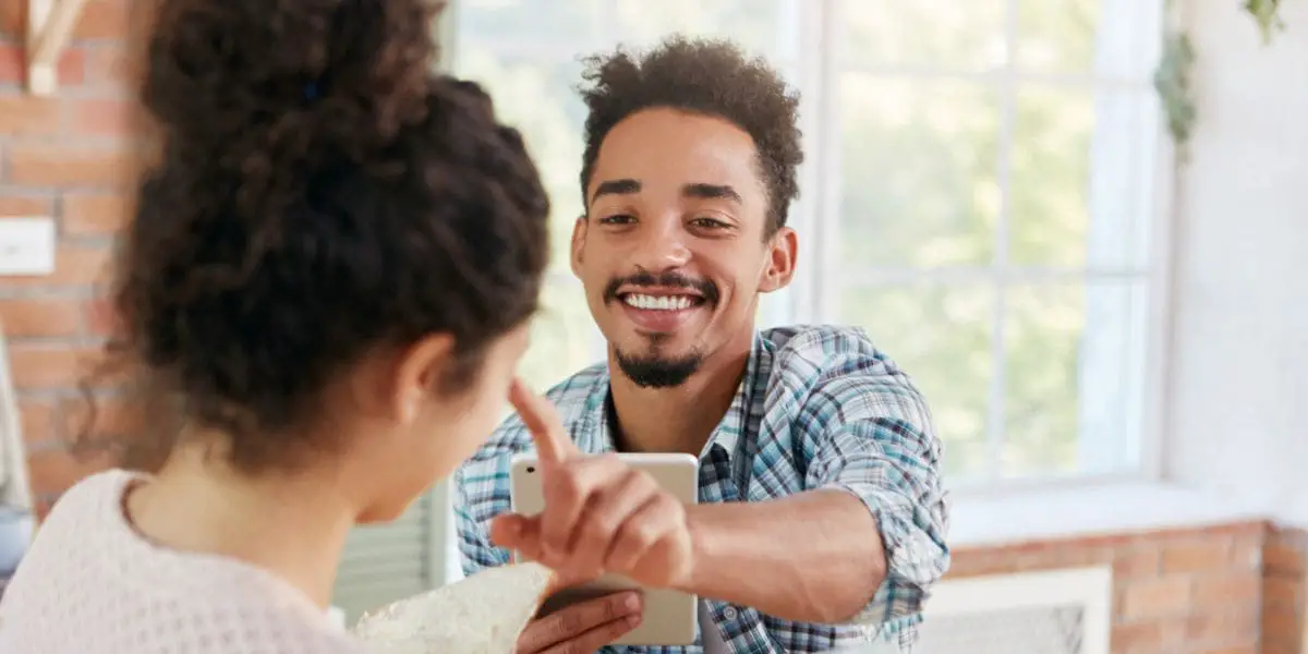 Relacionamento saudável: Homem sorridente coloca o dedo na ponta do nariz de uma mulher como forma de brincadeira.