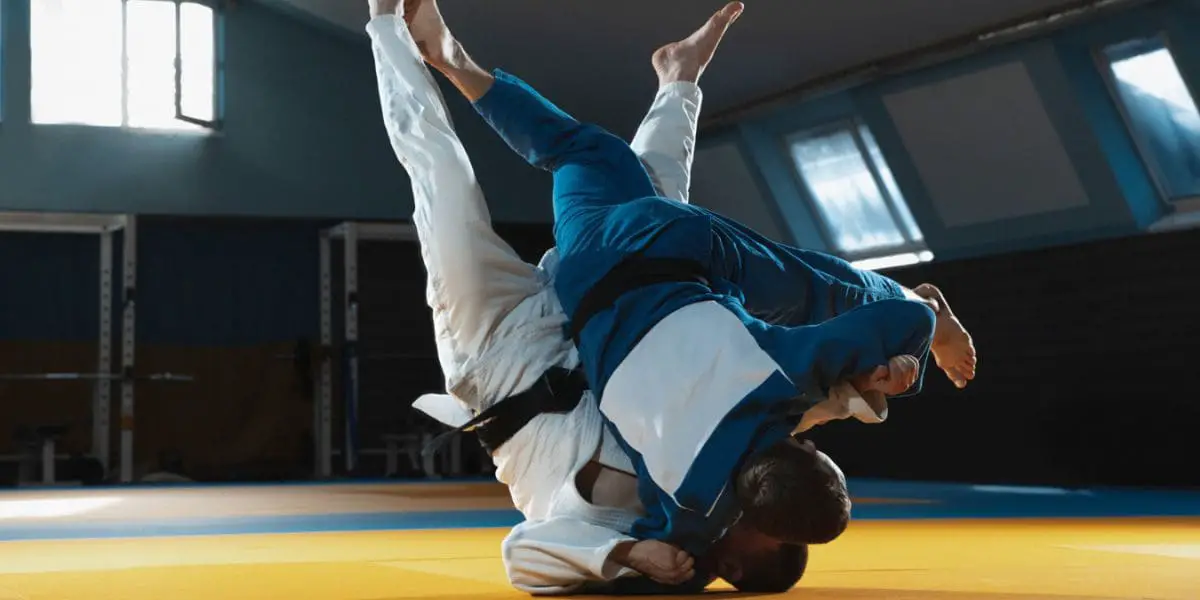 Artes marciais: Homens de kimonos azul e branco lutando Judô