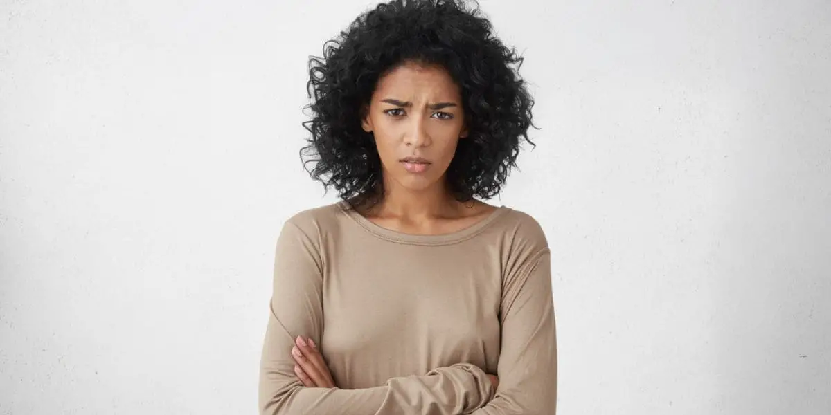 Reclamação: Mulher de cara emburrada com os braços cruzados.