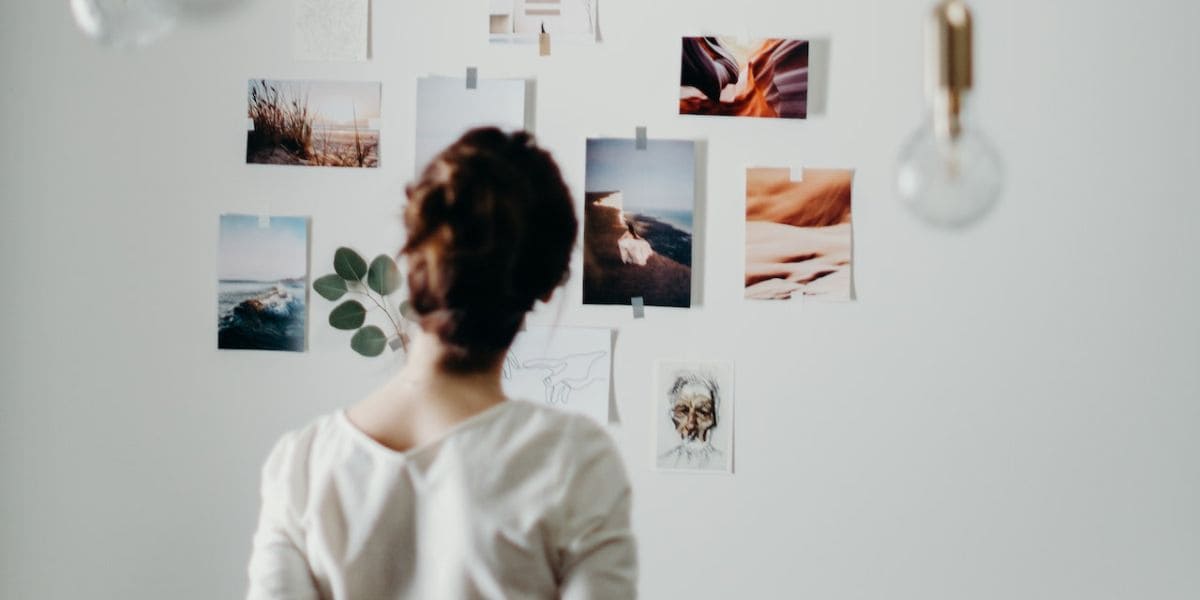 Como Manter a Motivação de Forma Estratégica: Mulher de costas observando diversas fotos coladas na parede