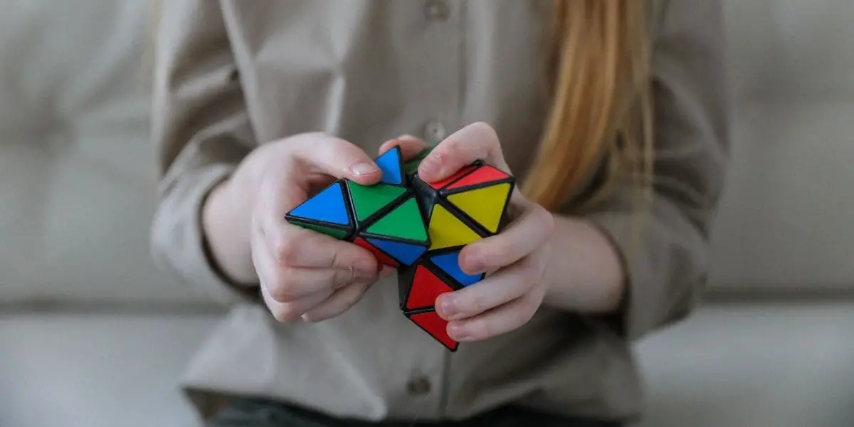 Mente Afiada: Mulher loira montando um Pyraminx.