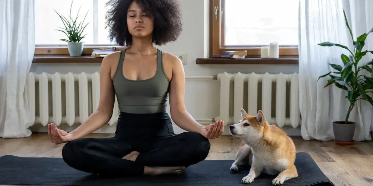 Mulher sentada em meditação ao lado de seu cachorro.