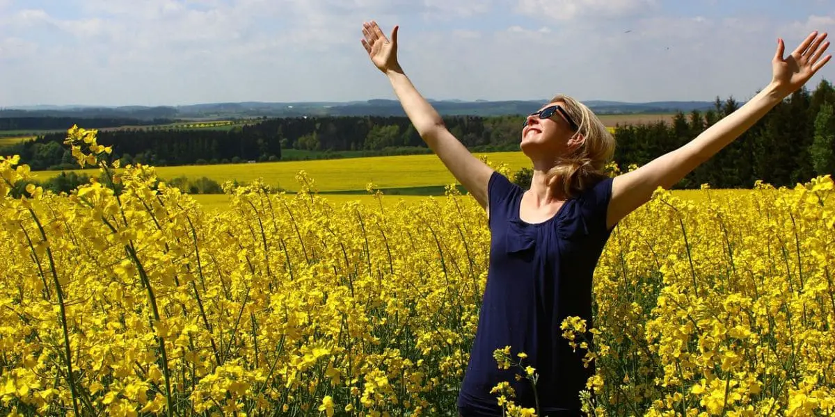 Saúde e bem-estar: Mulher sorridente com os braços abertos em um campo de girassóis