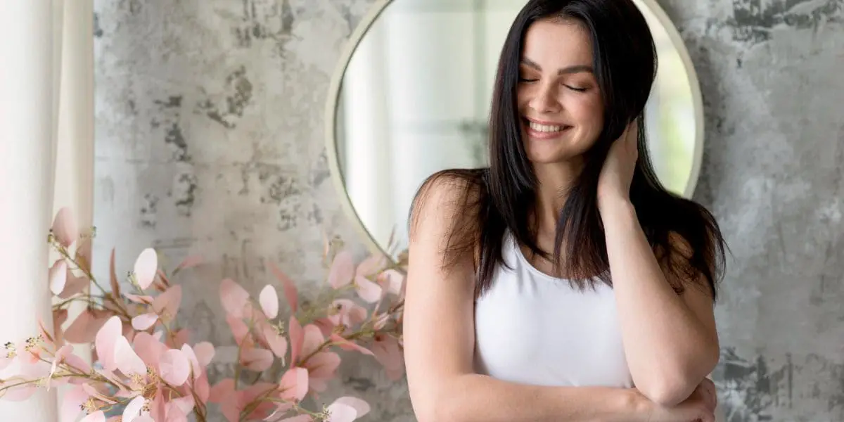 Mente positiva: Mulher sorridente com a mão nos cabelos.