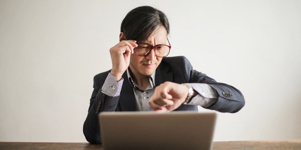 Gestão de Tempo: Senhor de terno olhando as horas em seu relógio de pulso.